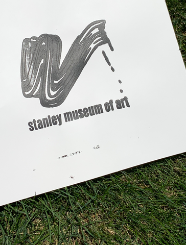 An image of a test print on paper, with black ink, laying on the grass outdoors.