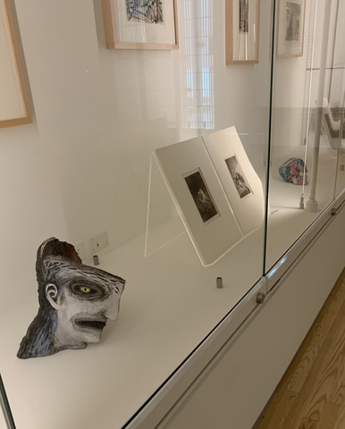 An image of the interior of the Visual Lab, with different sculptural artworks and prints visible inside a glass case.