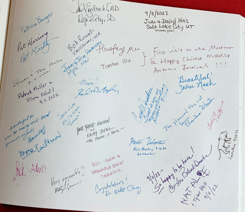 A photograph of the Stanley Museum of art guestbook. Signatures and written messages in different colors fill the large white pages.