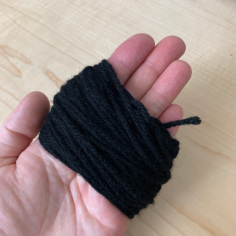 Black yarn is wrapped in loops around a person's palm.