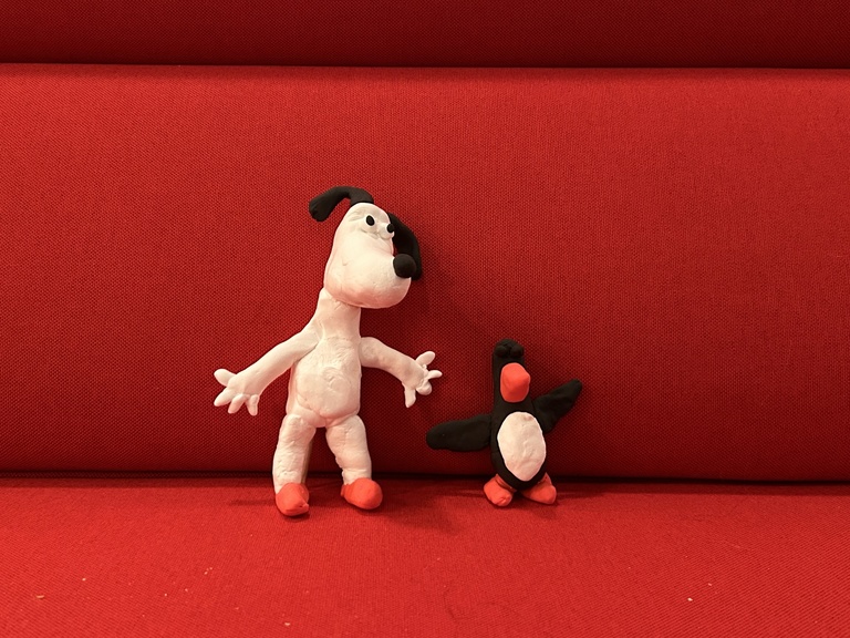 Two clay creations sit on the red couches in the museum lobby. They're both characters from the Wallace and Grommit short we watched at the event: Grommit the dog and a penguin.