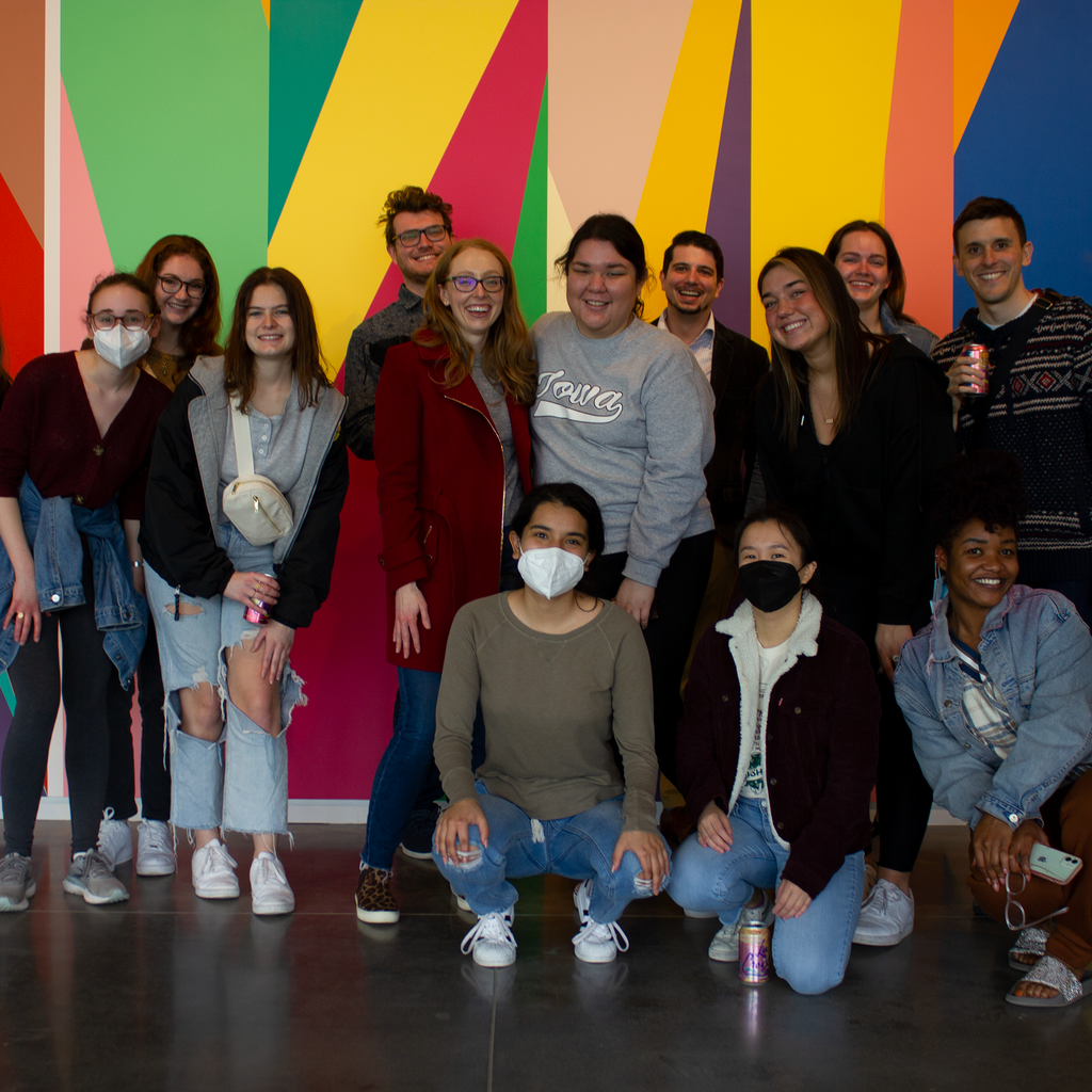 A group of University of Iowa students stand in front of the mural entitled "Surrounding," by artist Odili Donald Odita, that is painted in the lobby of the Stanley Museum of Art.
