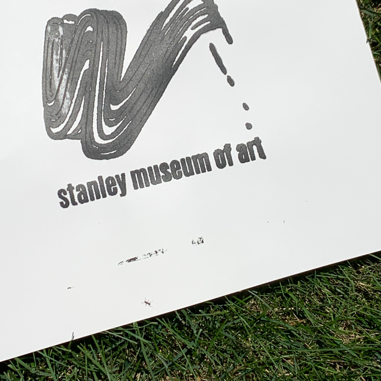 An image of a test print on paper, with black ink, laying on the grass outdoors.