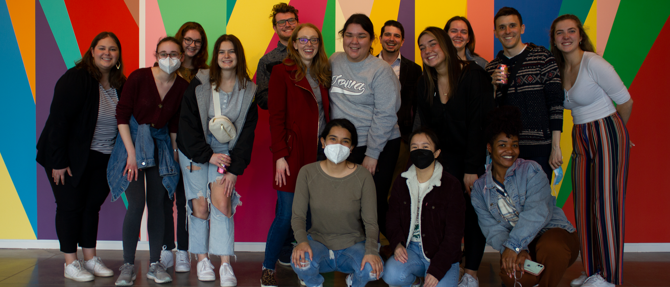 A group of University of Iowa students stand in front of the mural entitled "Surrounding," by artist Odili Donald Odita, that is painted in the lobby of the Stanley Museum of Art.
